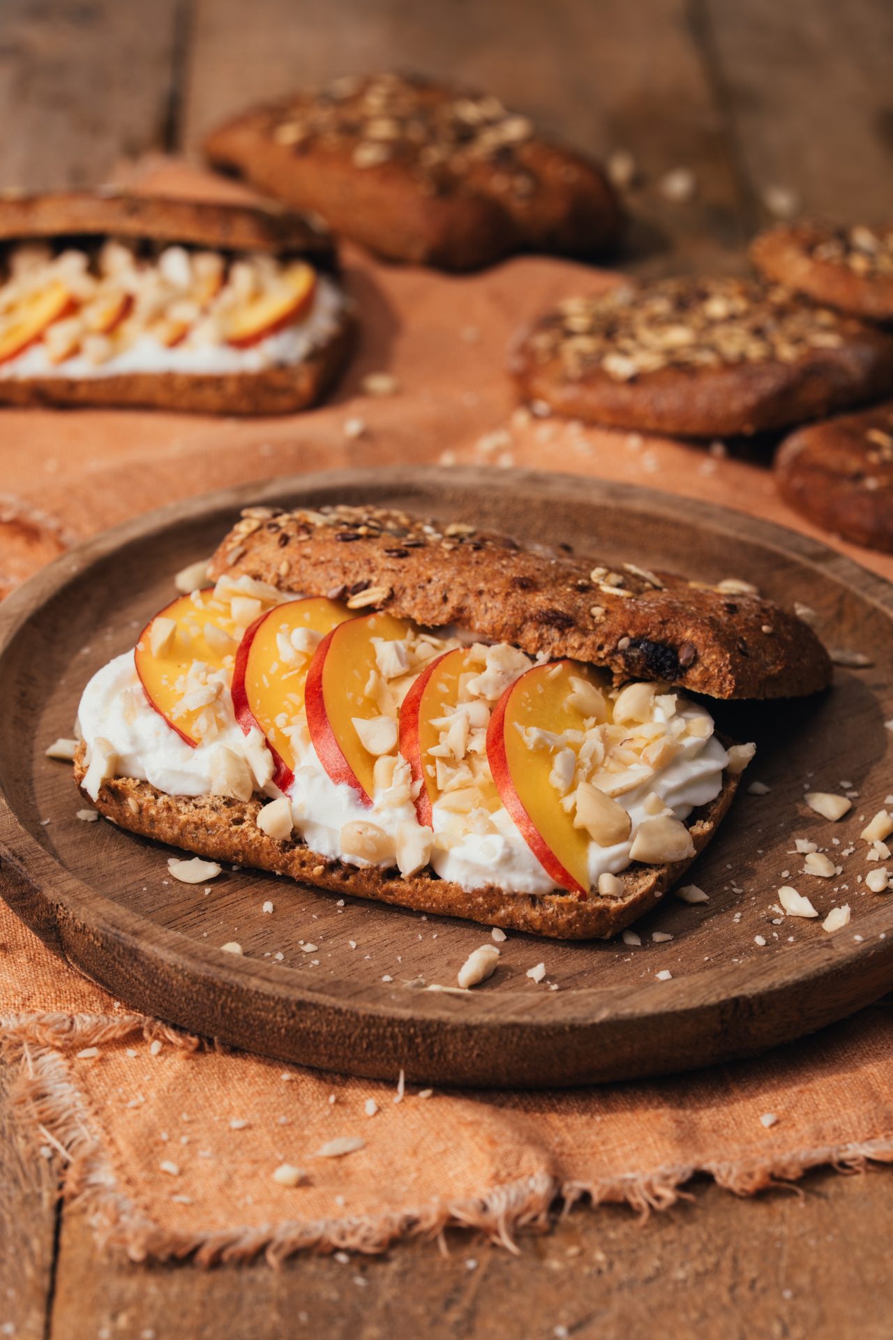 barretta con frutti e semi farcita con yogurt greco, pesca tagliata e granola di mandorle