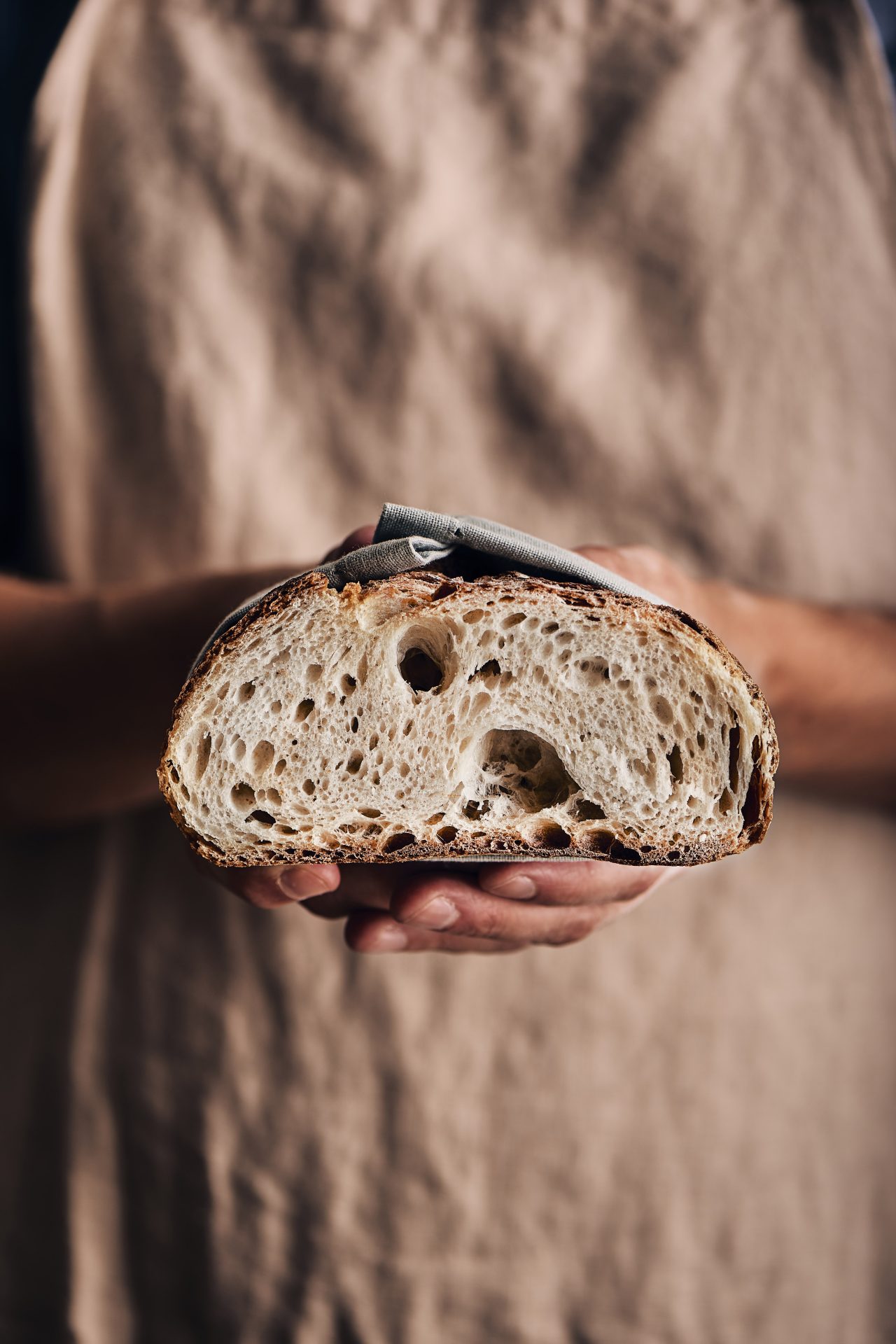 Fornaio che tiene in mano il pane e mostra la perfetta lievitazione